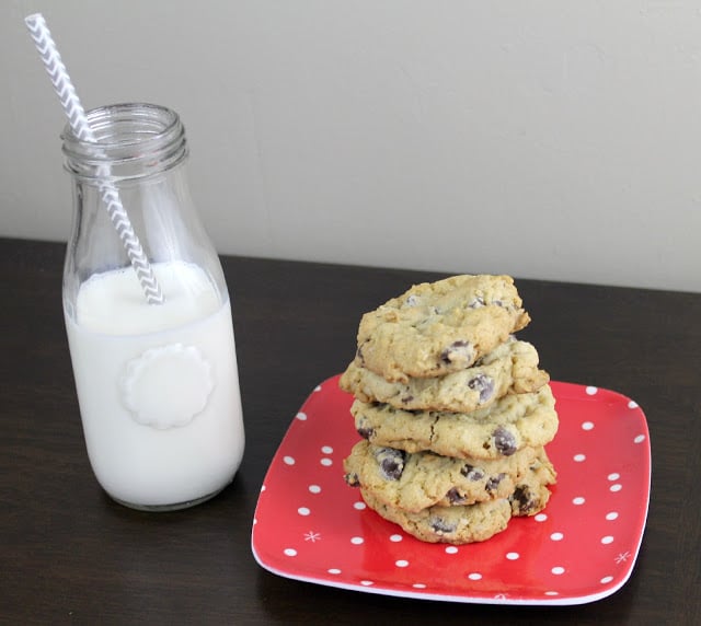 stacked chocolate chip cookies on a plate next to a glass of milk
