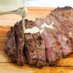 Grilled Ribeye with Garlic Blue Cheese Mustard Sauce on a cutting board and sliced with sauce on top