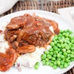 Salisbury steak on a plate with potatoes and peas