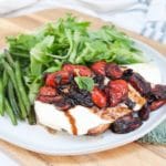 grilled caprese chicken plated with green beans and a salad.