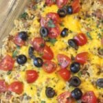 Cheese covered ground beef and rice. Topped with chopped tomatoes, sliced olives in a casserole dish
