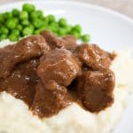 no peek beef tips on a plate with mashed potatoes and peas