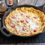 Bread pudding studded with cherries in a cast iron pan