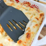 Chicken enchiladas in a baking dish with a spatula