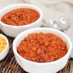 venison chili in bowl with cheese on the side