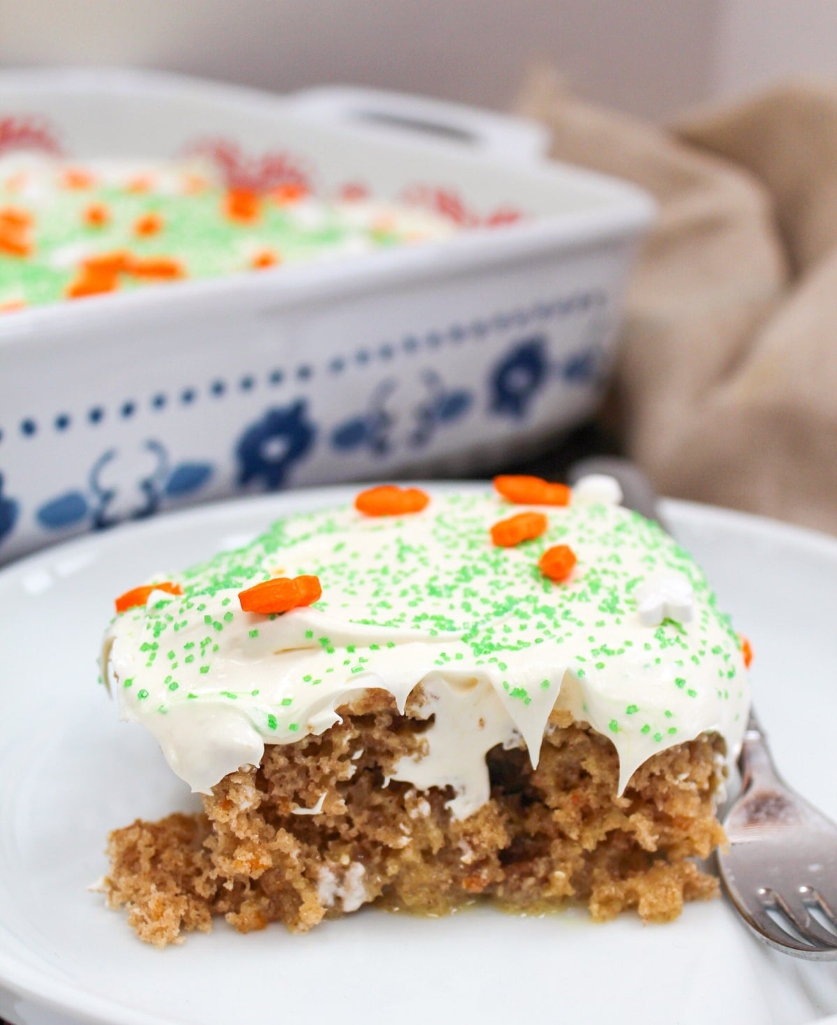 carrot cake poke cake on a white plate with a fork