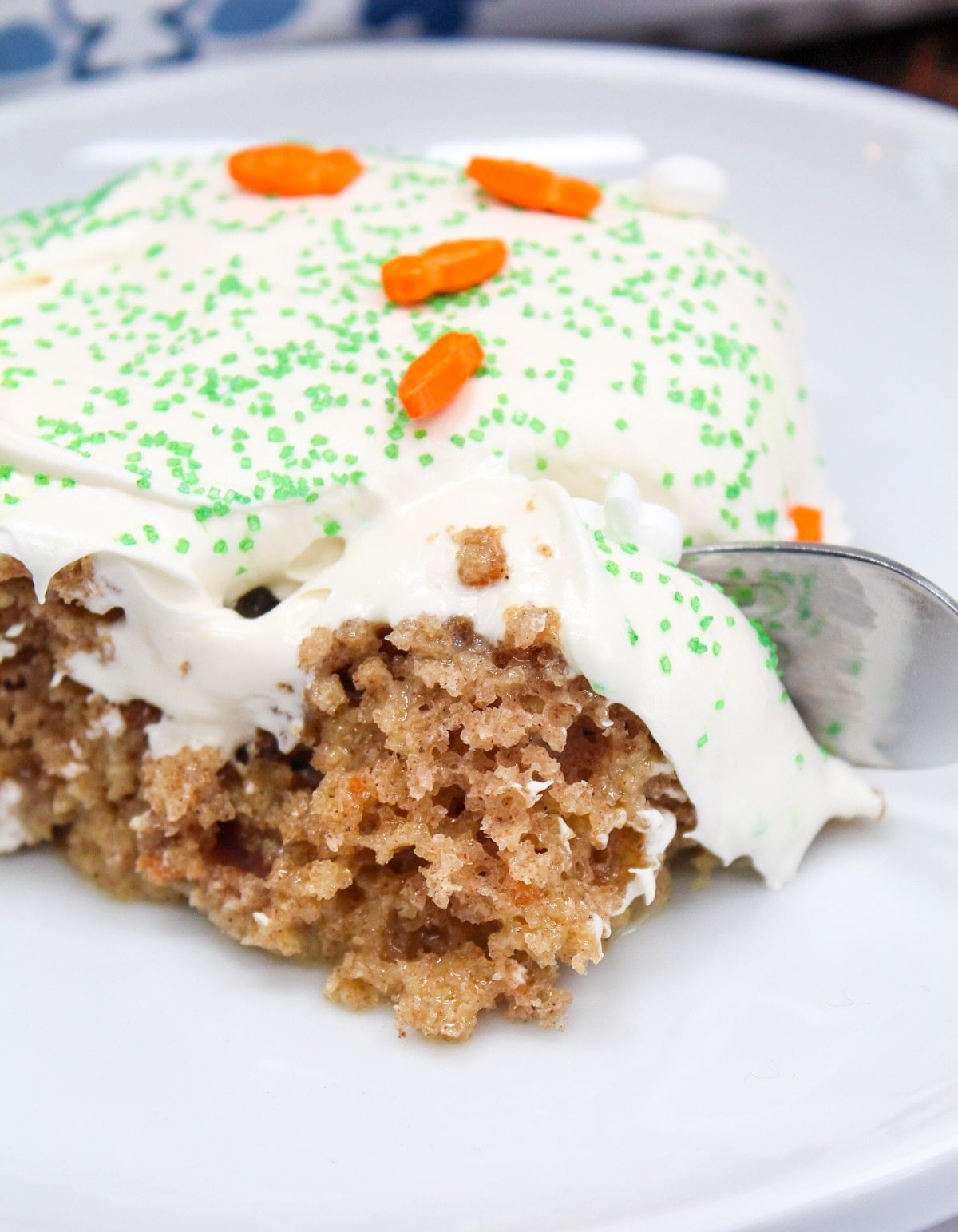 carrot cake poke cake on a white plate with a fork