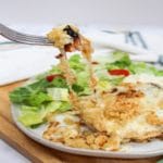 Longhorn Steakhouse Parmesan Chicken on a plate with a piece cut from the chicken