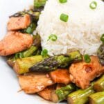 chicken and asparagus stir fry in a bowl with rice.