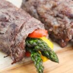 steak and asparagus roll-ups on a cutting board