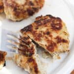 chicken formed into sausage patties. Cooked in a skillet till golden brown and served on a white plate and cut with a fork.