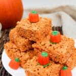 orange rice krispie treats cut into squares and stacked. Topped with a candy pumpkin.
