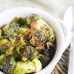 cooked brussels sprouts and bacon in a white bowl.