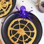 pancakes shaped like a round spider web with a plastic purple spider on the side.