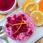 Pink overnight oats topped with chopped dragon fruit and citrus zest in a glass bowl.