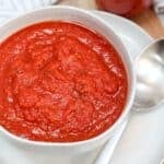 red tomato sauce in a white bowl with a silver spoon.