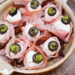 mozzarella balls wrapped in ham and topped with a black olive slice with pesto.