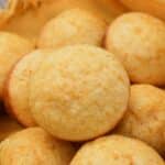 Muffins in a basket with a yellow cloth. Muffins are stacked on each other.